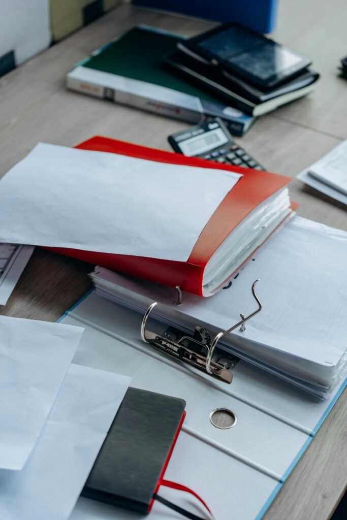 pexels-photo-8297536-8297536 Tidy office desk with binders, papers, and stationery, ideal for business or education themes.